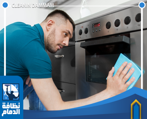 فني ينظف الفرن بعناية لإزالة الدهون والبقع وتحسين مظهر المطبخ.